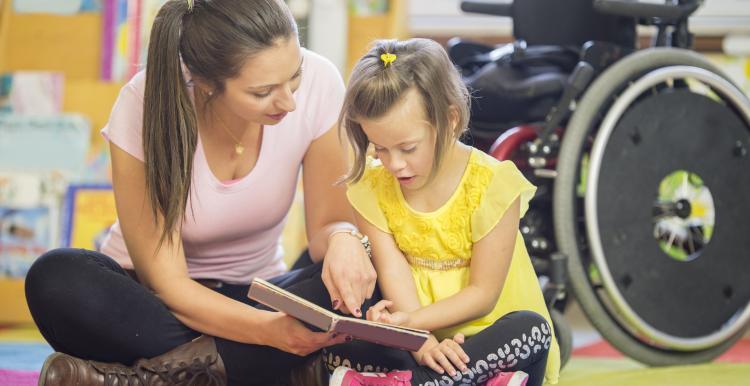 Photo of a young woman and daughter reading a book