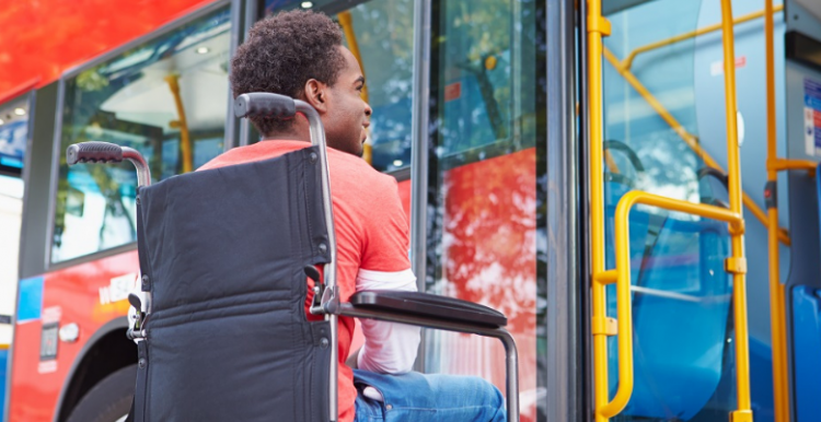 man in wheelchair waiting to board a bus