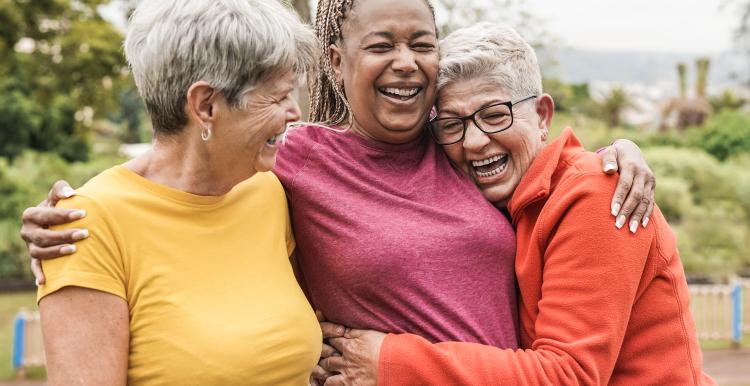 Three women outdoors, laughing and hugging