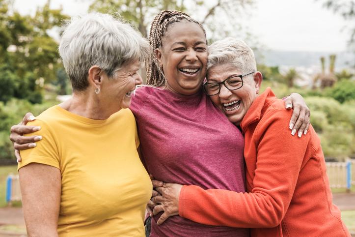 Three women outdoors, laughing and hugging