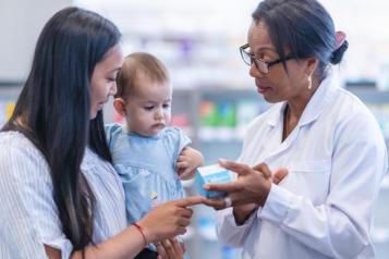 A woman and baby talking to a pharmacist in a pharmacy