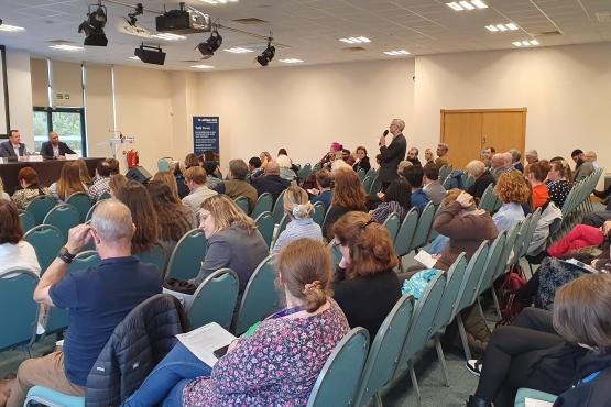 A member of the audience puts a question to a panel of experts at our Summit event. Audience members are watching.