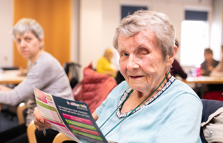 older woman holding a flyer 